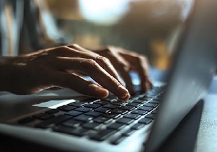 Hands typing on a laptop