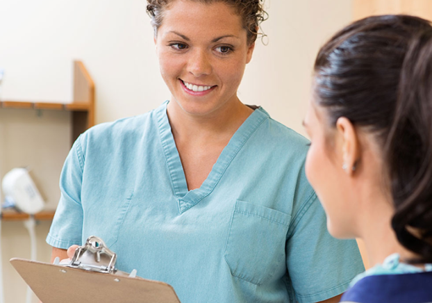A smiling female medical assistant conferring with a patient.