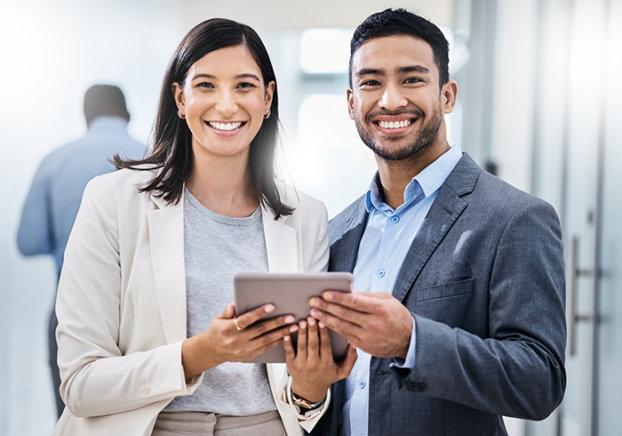 Two businesspeople standing together and holding a digital tablet in an office